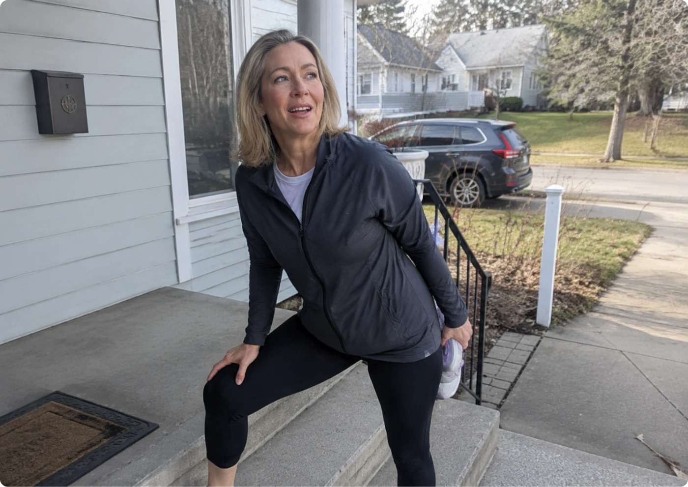 A woman stretching on her front steps after a walk